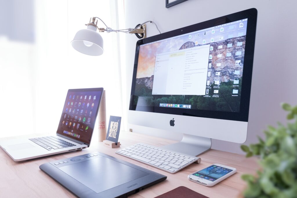 A desk with two computers and a cell phone.