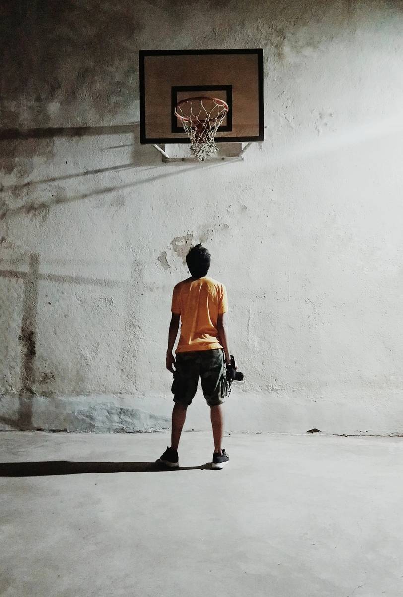 A boy is playing basketball in an old building.
