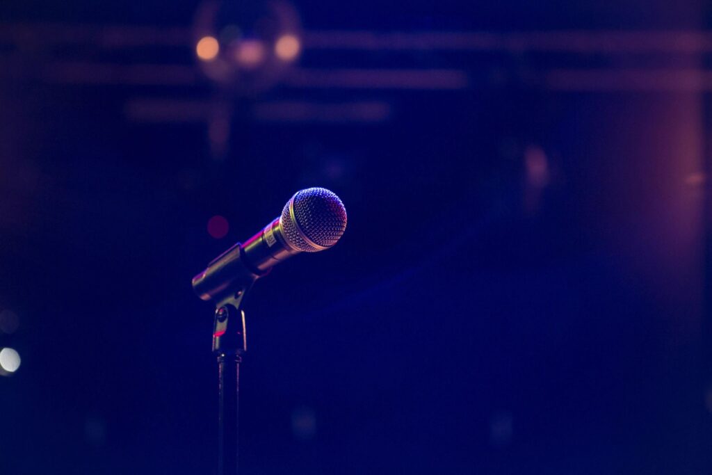 A microphone is on the stand in front of a dark background.