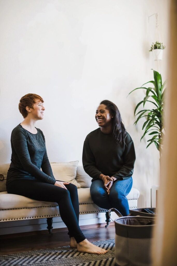 Two people sitting on a couch talking to each other.